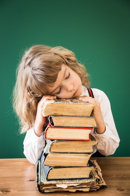 Schooljongen zit aan de balie in de klas. Gelukkig kind tegen groen bord. onderwijs concept