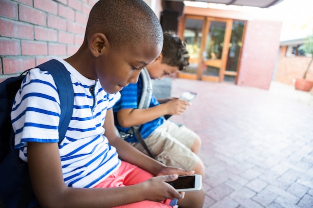 Schooljongens met behulp van mobiele telefoons op gang op school