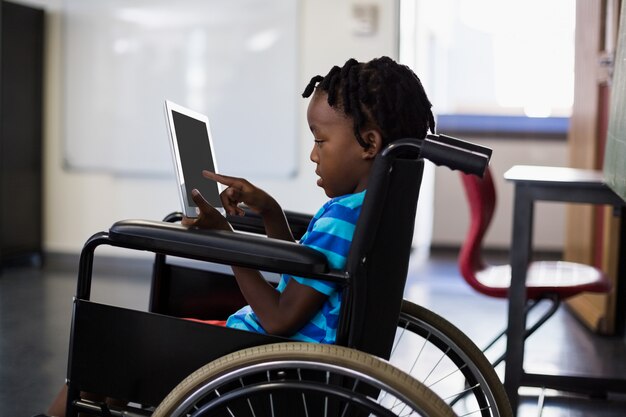 Schooljongenzitting op rolstoel en het gebruiken van digitale tablet