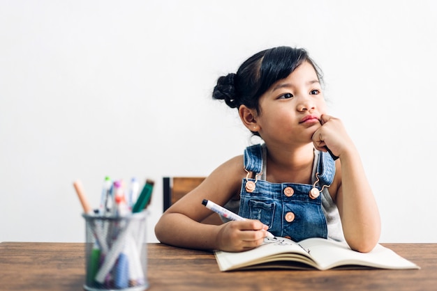 Schoolkid girl learning and writing on notebook with pencil making homework