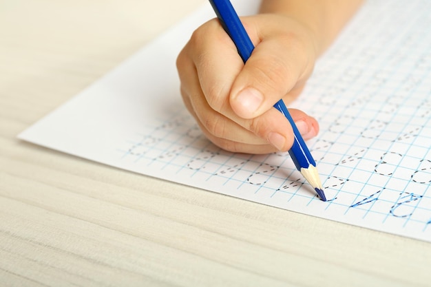 Schoolkid leert schrijven op een vel papier close-up