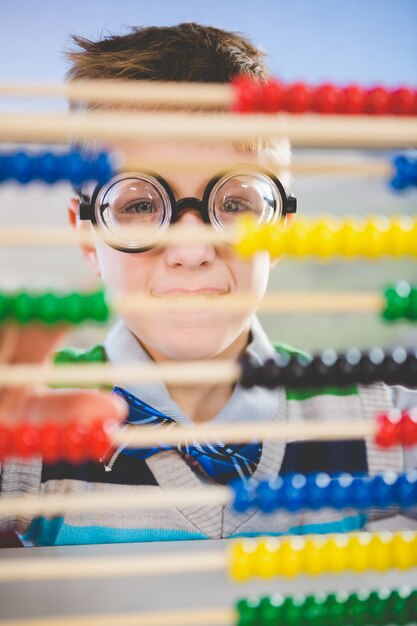 Schoolkid looking through abacus in classroom