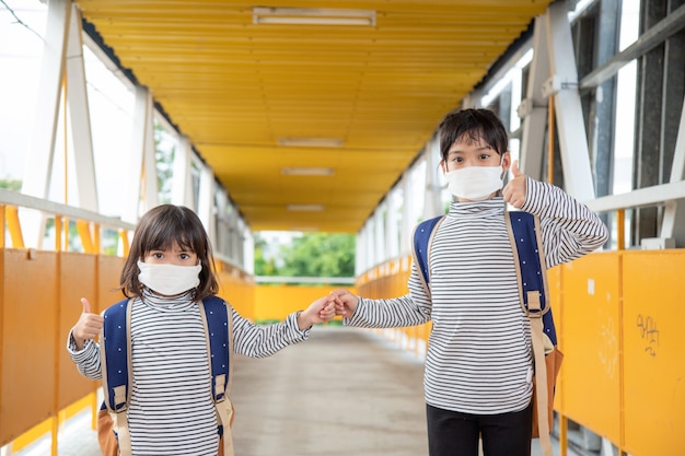 Schoolkind dat een gezichtsmasker draagt tijdens de uitbraak van het coronavirus Klein meisje gaat terug naar school