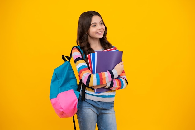 Schoolkind tiener student meisje houd boek op gele geïsoleerde studio achtergrond School en onderwijs concept Terug naar school Gelukkige tiener positieve en lachende emoties van tienermeisje