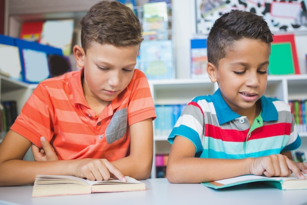 Schoolkinderen die boek in bibliotheek lezen