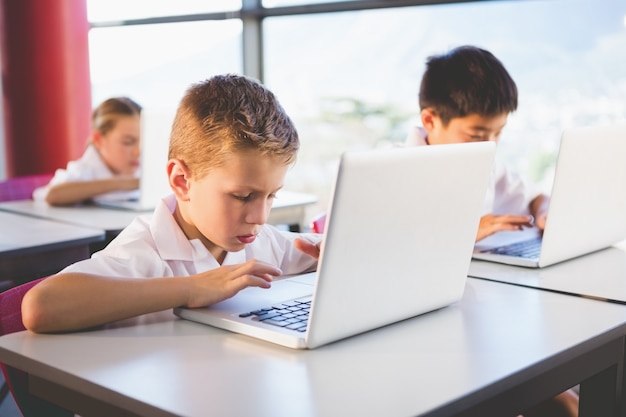 Schoolkinderen die laptop in klaslokaal gebruiken