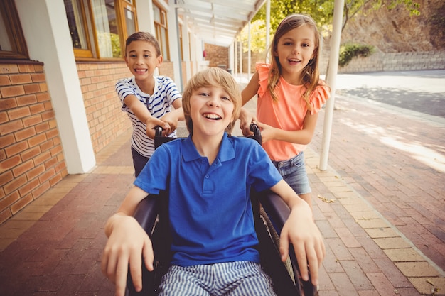 Schoolkinderen duwen een jongen op rolstoel