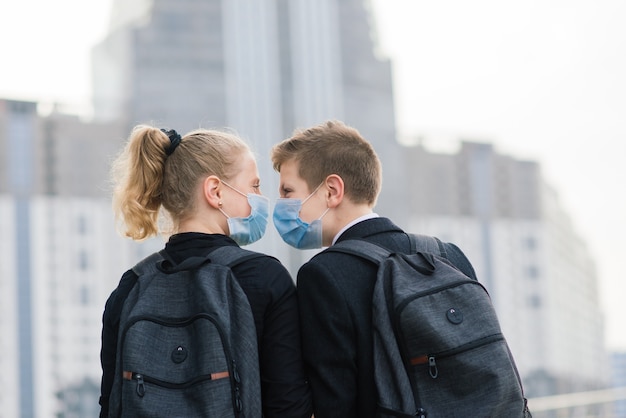 Schoolkinderen, een jongen en een meisje met medische maskers lopen door de stad.