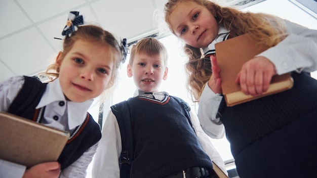 Foto schoolkinderen in uniform poseren samen voor een camera in de gang conceptie van onderwijs