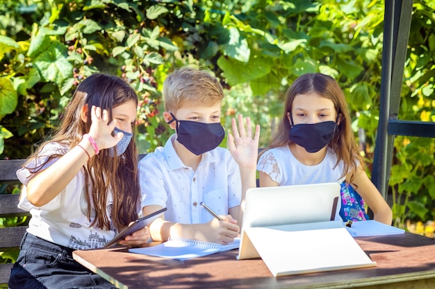 Foto schoolkinderen met beschermende gezichtsmaskers kijken thuis naar online onderwijslessen