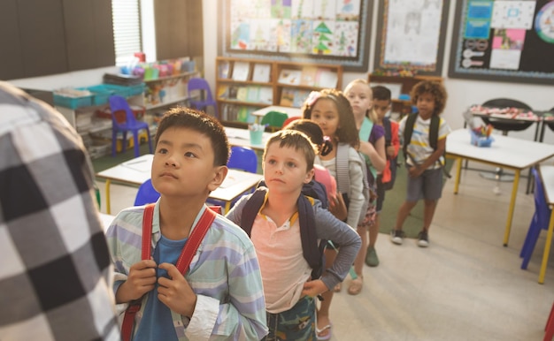 Foto schoolkinderen staan en vormen een rij in de klas op school