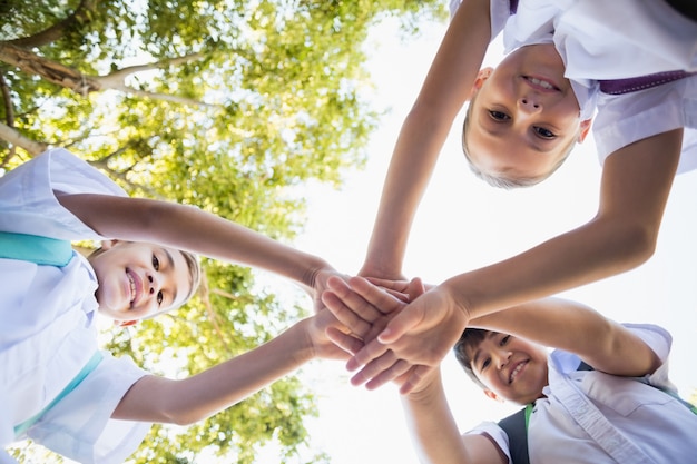 Schoolkinderen stapelen handen in campus