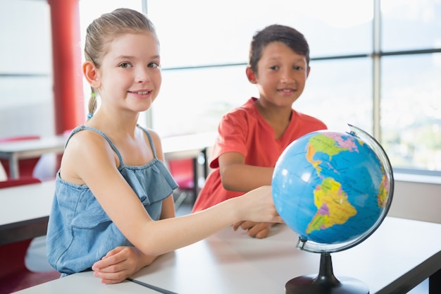 Schoolkinderen studeren wereldbol in de klas