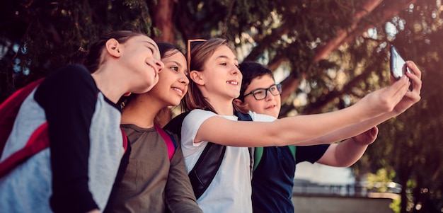 Schoolkinderen zitten in de schaduw en nemen selfie op straat