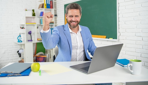 Schoolleraar in klaslokaal met computer bij bordsucces