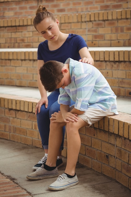 Schoolmeisje dat haar droevige vriend troost op stappen in campus