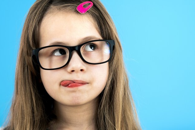 schoolmeisje dat het kijken glazen draagt die op blauwe achtergrond worden geïsoleerd