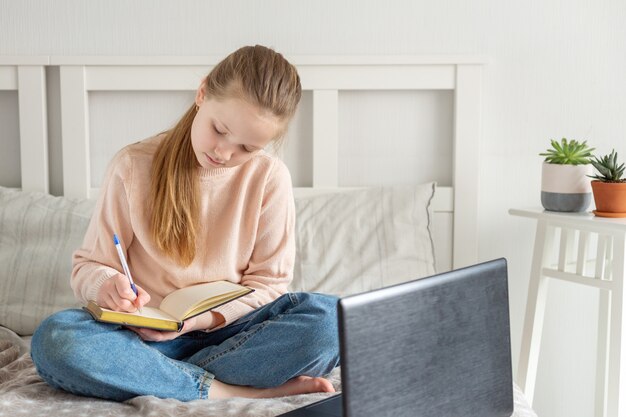 Schoolmeisje dat thuis met behulp van laptop bestudeert. Online onderwijs, quarantaineconcept