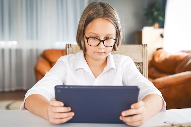 Schoolmeisje die zich bezighouden met thuisonderwijs kijken naar online leercollege op laptop thuis Kid bijwonen van externe virtuele schoolklas luisteren naar leraar Leren op afstand thuis met technologie