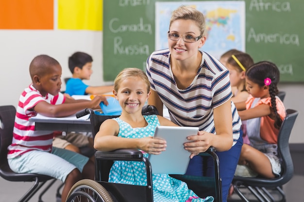 Schoolmeisje en leraar die digitale tablet in klaslokaal gebruiken