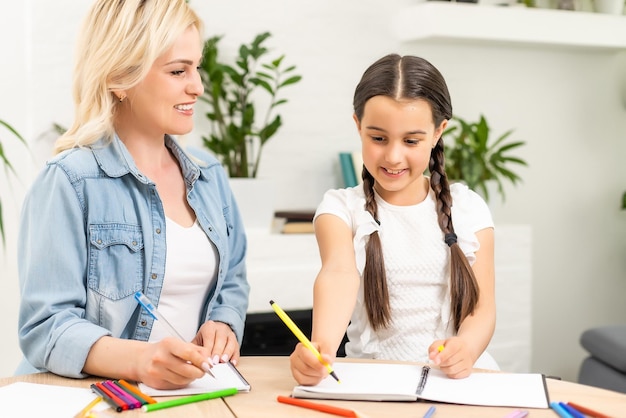 schoolmeisje en moeder samen huiswerk thuis.