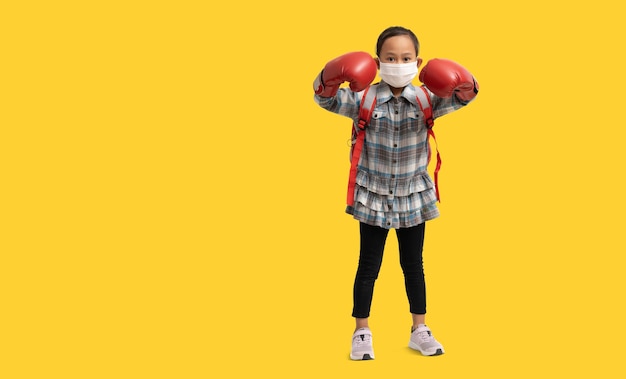 Schoolmeisje Gelukkige Aziatische student die bokshandschoenen draagt en een medisch gezichtsmasker draagt Volledig lichaamsportret isolaat op gele achtergrond met uitknippad voor ontwerpwerk