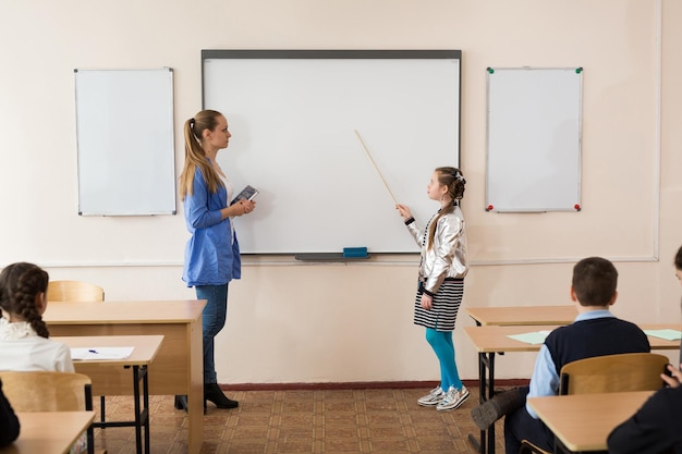 Schoolmeisje in de buurt van het bord met een pointer