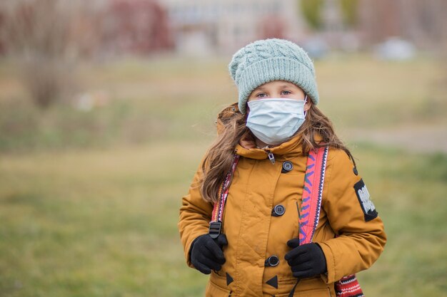 Schoolmeisje in medisch masker met bagpack