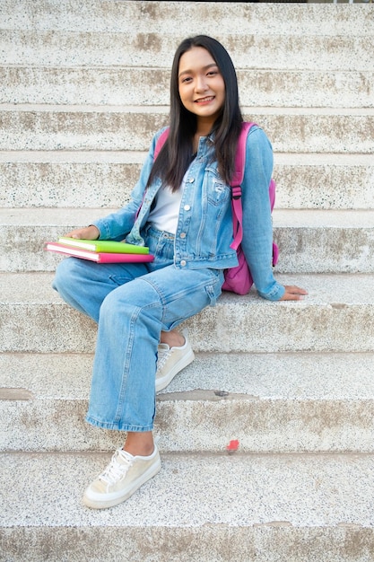 Schoolmeisje Lachend en zittend op het boek van de trapgreep op school