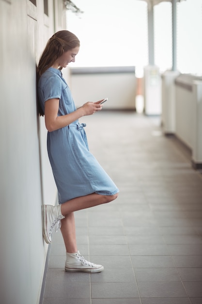 Schoolmeisje met behulp van mobiele telefoon in gang