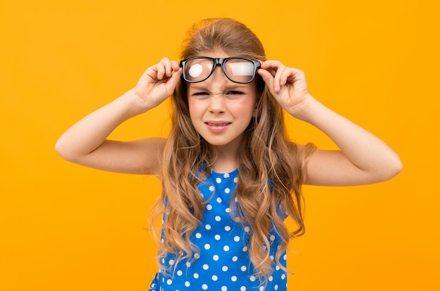 Schoolmeisje met bril heft bril over haar ogen, slecht ziende kind