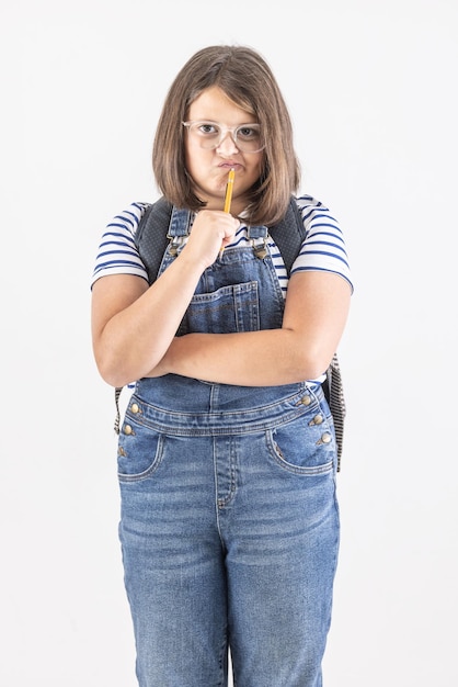 Schoolmeisje met bril houdt armen gekruist en potlood dicht bij haar mond en denkt hard