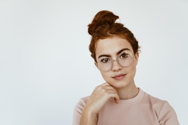 Schoolmeisje met bril om het zicht in een lichte kleurenstudio te verbeteren