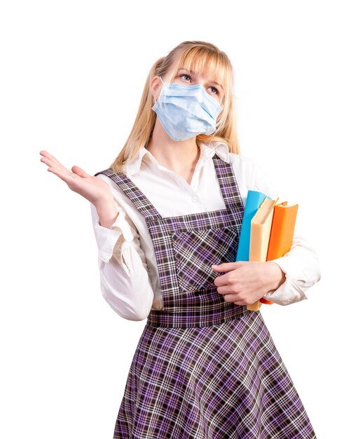 Foto schoolmeisje met een medisch masker op haar gezicht houdt schoolboeken op een wit