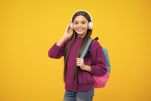 Schoolmeisje met koptelefoon op een geïsoleerde studio achtergrond School en muziekconcept