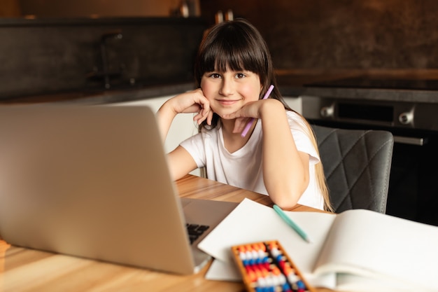 Schoolmeisje na online leren met een laptop. Meisje studeert en maakt thuis huiswerk met een videogesprek. Onderwijs op afstand