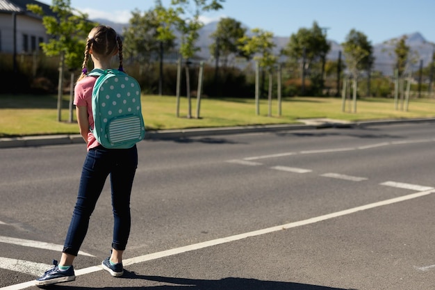 Schoolmeisje op zoek naar verkeer tijdens het wachten om de weg over te steken