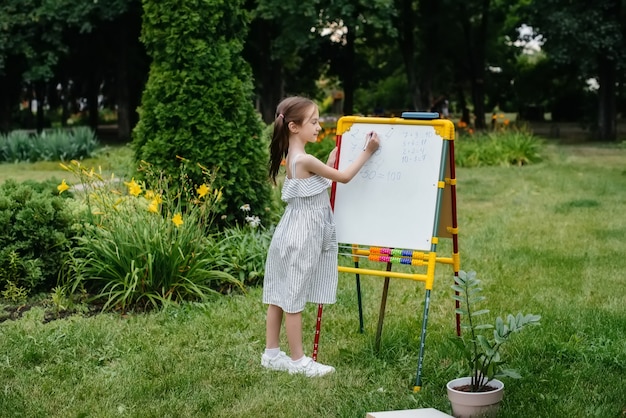 Schoolmeisje schrijft lessen op een schoolbord en houdt zich bezig met buitentraining