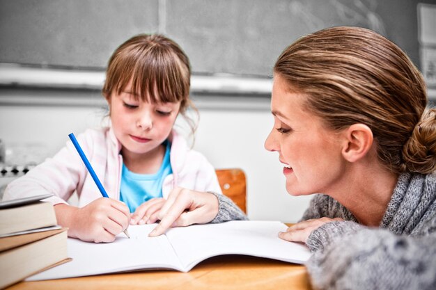 Schoolmeisje schrijft met haar lachende leraar in de klas