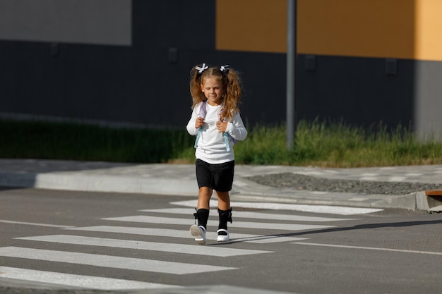 Schoolmeisje steekt de weg over bij een zebrapad