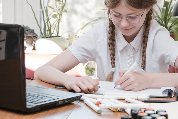 Schoolmeisje zelfisolatie met behulp van laptop voor zijn huiswerk. Meisje doet met behulp van digitale tablet informatie zoeken op internet tijdens covid 19 lock-down. Sociale afstand, E-learning online onderwijs