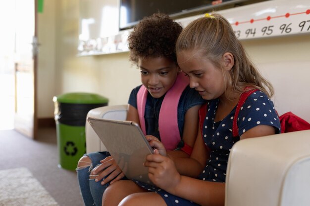 Foto schoolmeisjes kijken samen naar een tabletcomputer in een klaslokaal op de basisschool