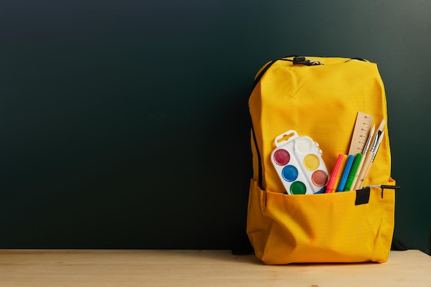 Schoolrugzak met kleurrijke schoolspullen op tafel