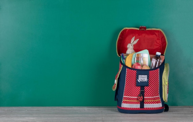 schooltas, witte houten tafel en schoolbord