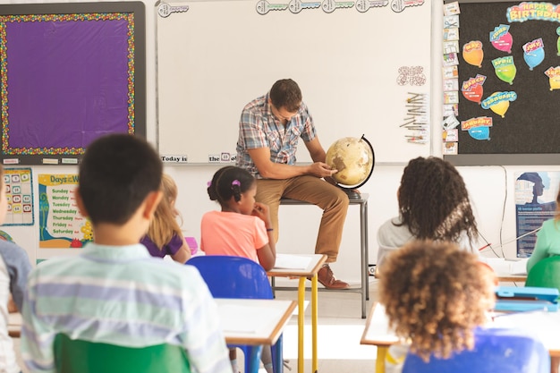 生徒に地球儀を学ぶ学校の先生