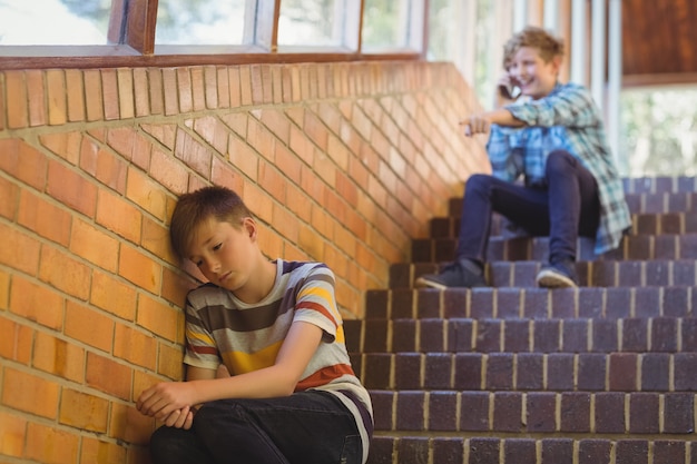 Schoolvriend die een trieste jongen in schoolgang pesten