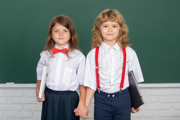 Schoolvrienden leren samen schoolmeisje en schooljongen in de klas op schoolkinderen vrienden houden vast