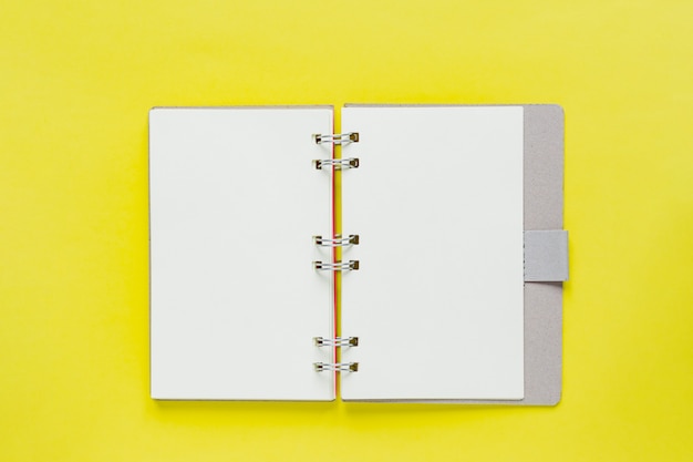 Schoon notitieboek voor doelen en resoluties bij het recyclen van papieren omslag. mockup voor uw ontwerp. Spiraalvormig notaboek op gele achtergrond.
