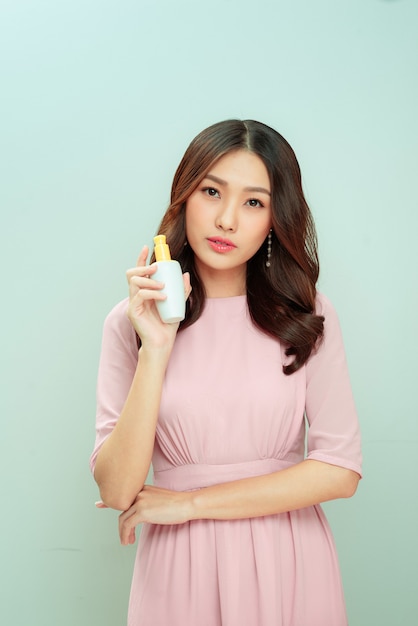Schoonheid aziatische vrouw houdt fles cosmetische crème lotion en vrolijk.