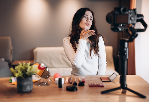 Schoonheid blogger mooie vrouw filmen dagelijkse make-up routine tutorial op camera. Influencer jonge vrouw live streaming cosmetica product review in thuisstudio. Vlogger baan. DIY make-up aanbrengen.